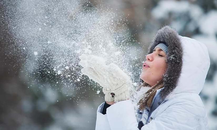 Frau pustet Schnee weg