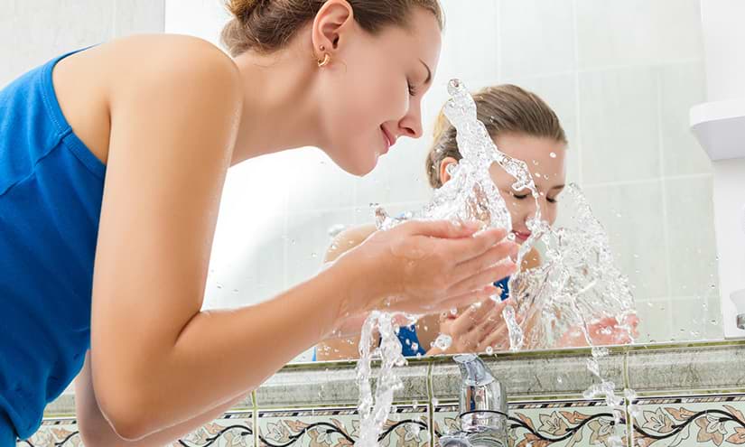 Frau reinigt ihr Gesicht mit Wasser